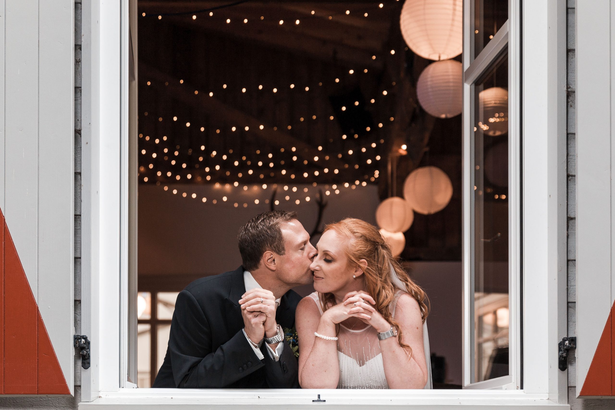 Hochzeitsbild eines Brautpaares. Das Hochzeitspaar Lehnt sich am Fenster der Hochzeitslocation an und posiert für den Hochzeitsfotograf.