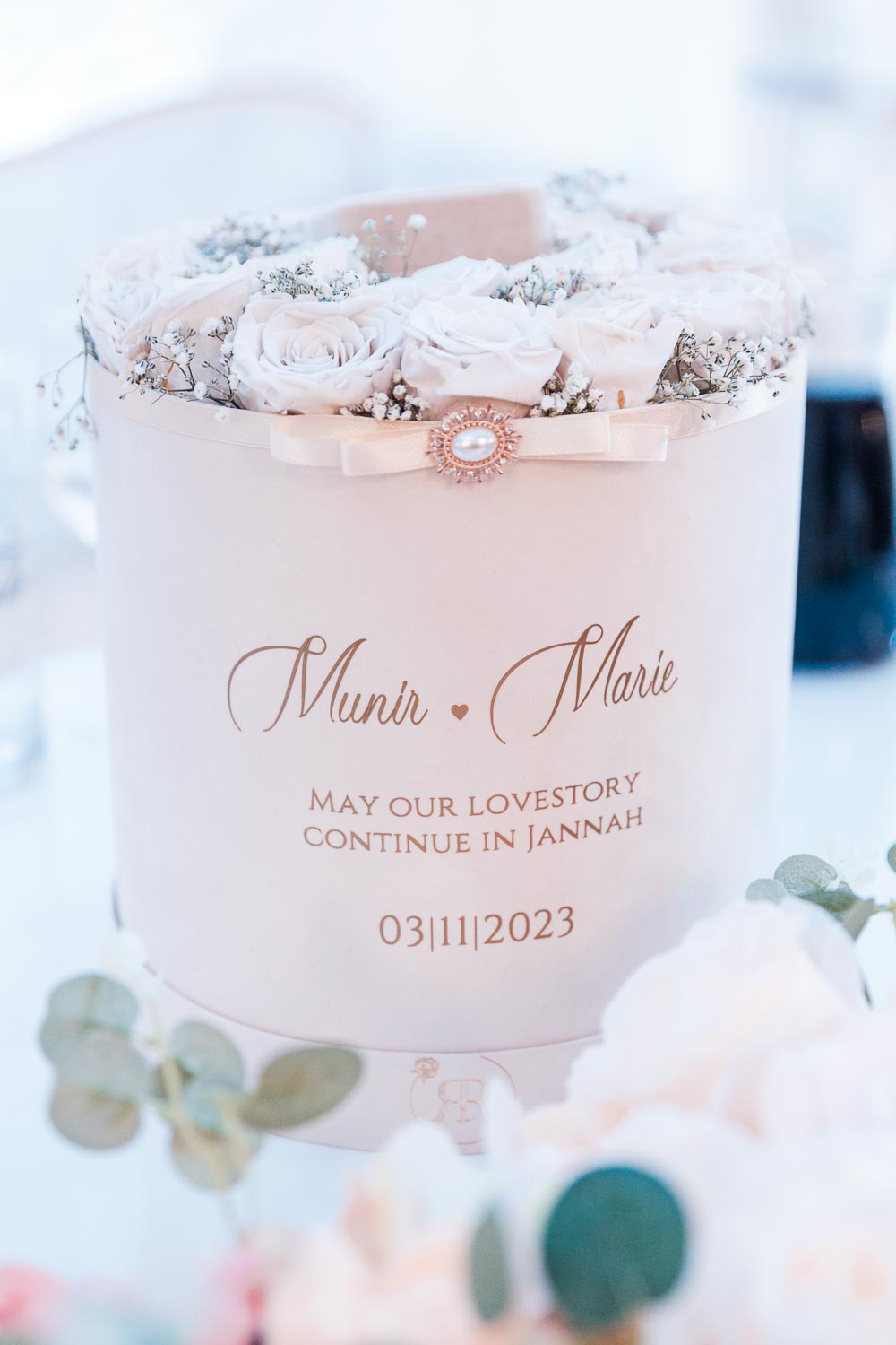 Hochzeitsgeschenk: Rosenbox mit weißen Rosen mit dem Namen des Brautpaares auf dem Tisch.