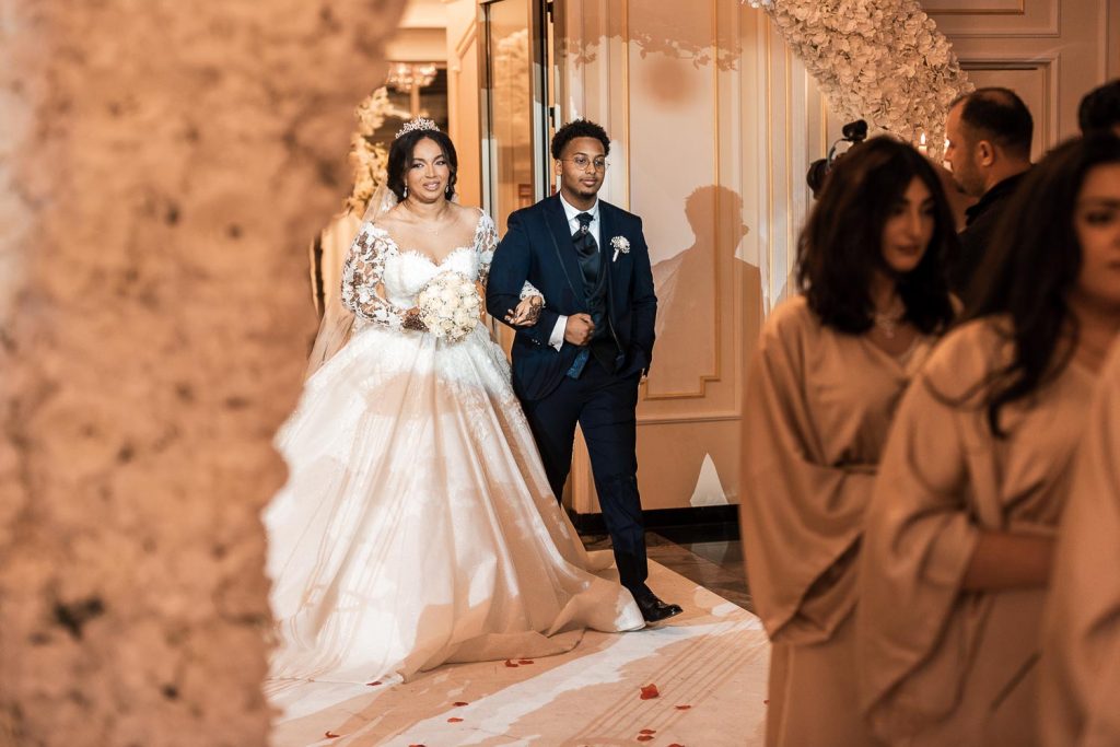 Hochzeit Fotograf - Afrikanische Braut im weißen Brautkleid schreitet mit ihrem somalischen Bräutigam in den Event Palast Köln Hürth Hochzeitssaal.