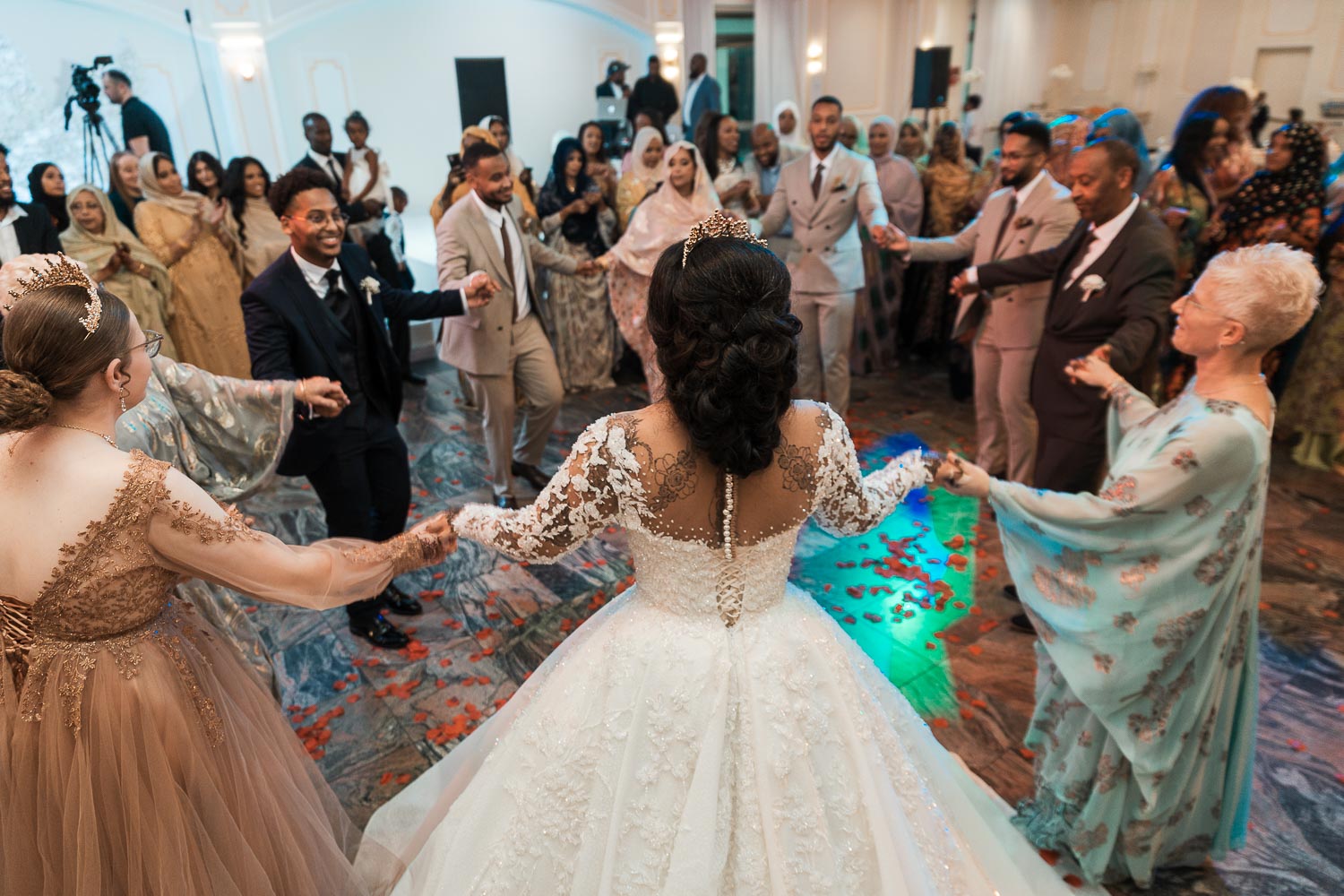 Braut und Bräutigam, Hand in Hand, tanzen im Kreis mit ihren Gästen.