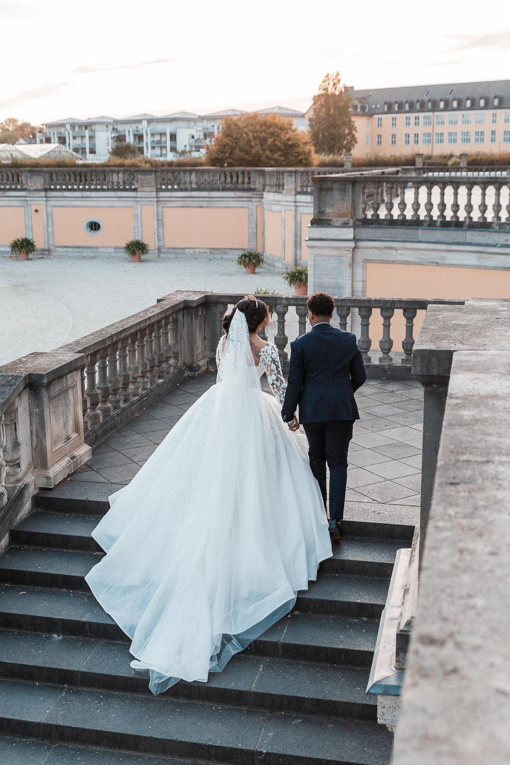 Braut und Bräutigam besteigen die Treppe zur Terrasse zum Schloss Augustusburg in Brühl. Ein natürliches Hochzeitsfoto welches umgestellt und aus der Situation heraus entstand.