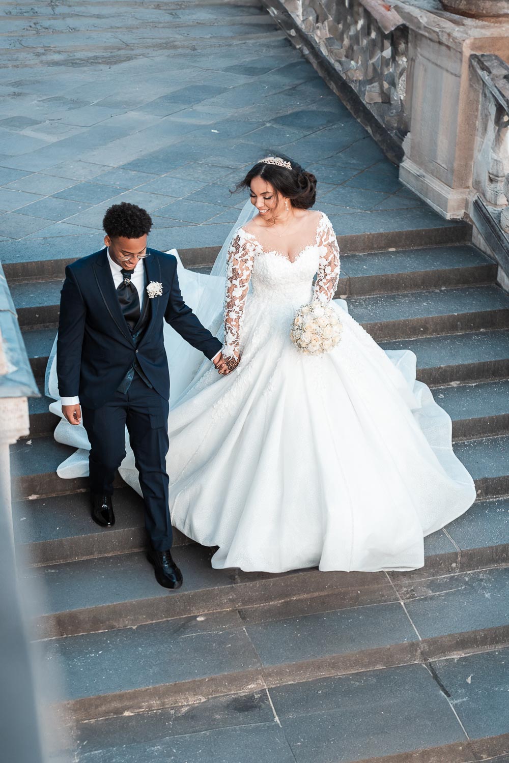 Braut und Bräutigam gehen die Treppe hinab zur Terrasse zum Schloss Augustusburg in Brühl. Ein natürliches Hochzeitsfoto welches umgestellt und aus der Situation heraus entstand.