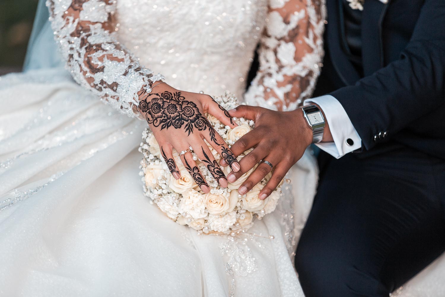 Brautpaar präsentiert die Hände auf dem weißen Braut Strauß während die Hände eine Herzform andeuten.