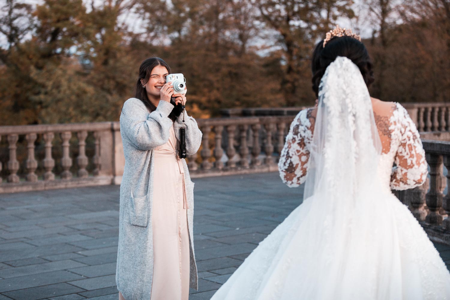 BridesMaids fotografiert die Braut mit ihrer Instax Kamera während der Hochzeitsfotograf die Braut von hinten und die BridesMaids von vorne ablichtet. Die Braut wird von den Brautjungfern mit ihrer Instax-Kamera fotografiert, während der Hochzeitsfotograf die Braut von hinten und die Brautjungfern von vorne ablichtet.