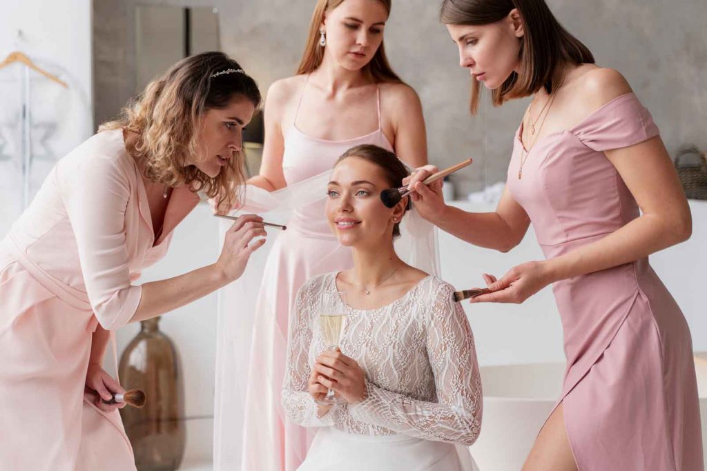 Braut beim Getting Ready, umgeben von Brautjungfern, die sie für die Hochzeit stylen – Symbol für entspannte Hochzeitsvorbereitung.