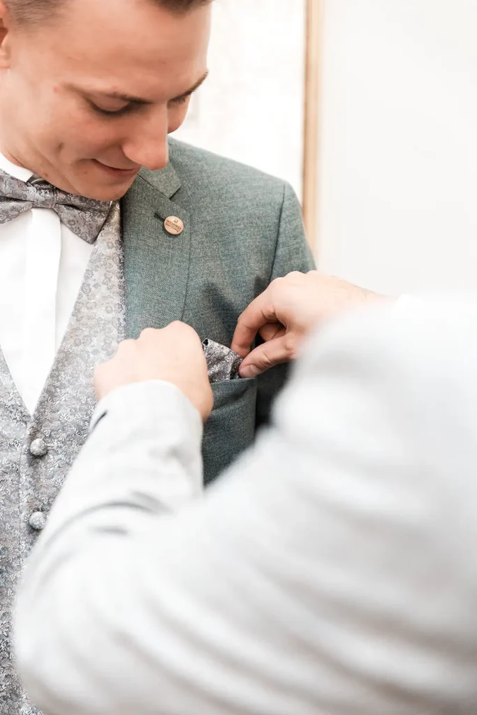 Einstecktuch wird beim Getting Ready des Bräutigams in die Brusttasche des Hochzeitsanzugs gesteckt