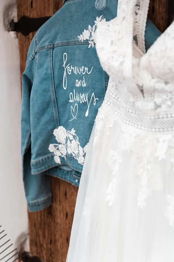 Weißes Brautkleid mit personalisierter Jeansjacke „forever and always“ beim Getting Ready