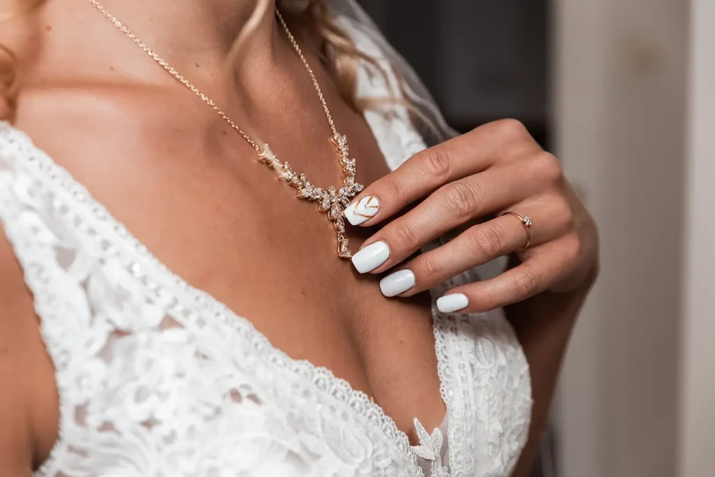 Detailaufnahme von Brautschmuck, Hochzeitsnägeln und Spitze des Brautkleids