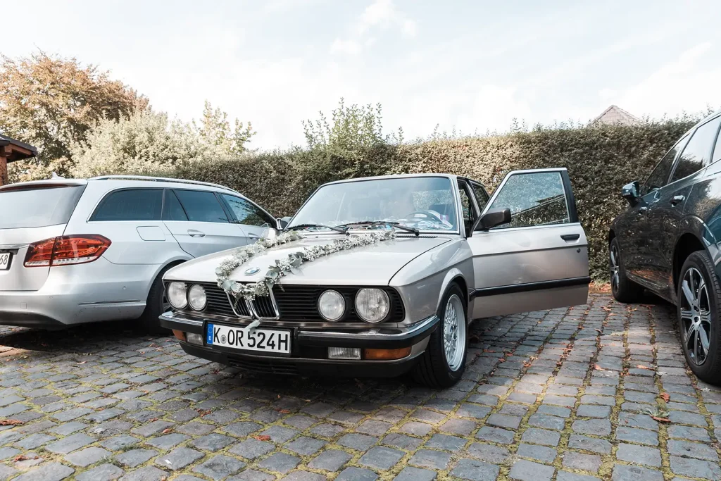 Klassischer BMW mit Blumenschmuck als Hochzeitsauto bei einer Hochzeit auf Schloss Burgbrohl