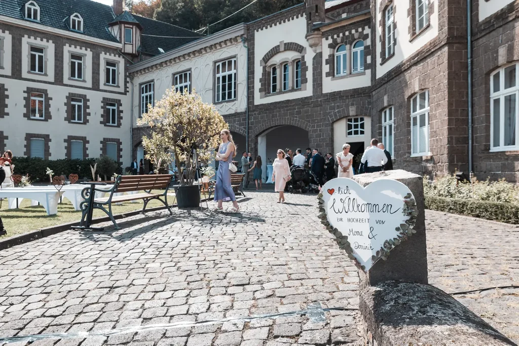 Historischer Außenbereich von Schloss Burgbrohl mit Hochzeitsgästen und Willkommensdekoration