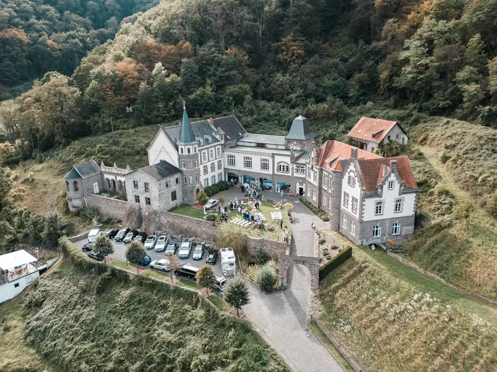 Schloss Burgbrohl als Hochzeitslocation in der Eifel aus der Luft mit Hochzeitsgesellschaft im Außenbereich
