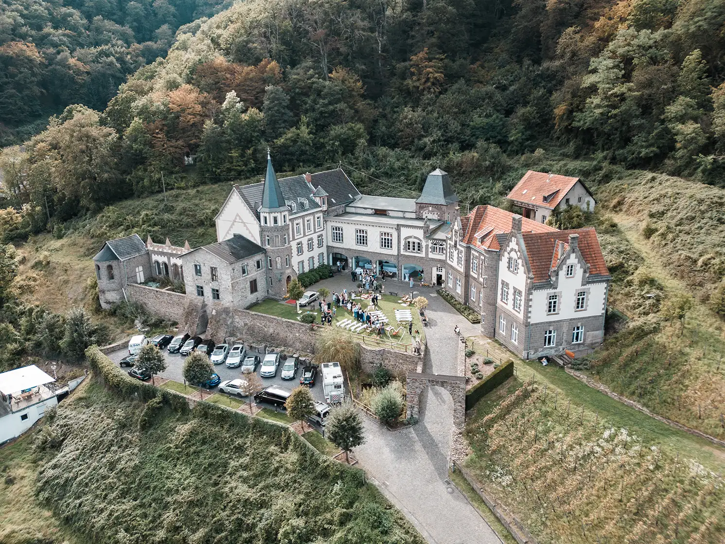 Schloss Burgbrohl als Hochzeitslocation in der Eifel aus der Luft mit Hochzeitsgesellschaft im Außenbereich