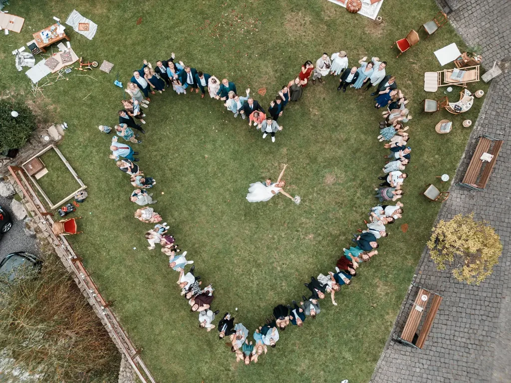 Hochzeitsgesellschaft bildet ein Herz um das Brautpaar bei einer Hochzeit auf Schloss Burgbrohl