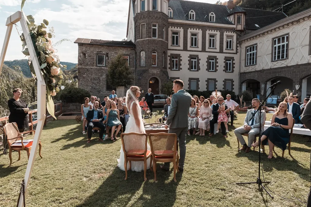 Brautpaar bei einer freien Trauung auf Schloss Burgbrohl mit Gästen vor historischer Schlosskulisse