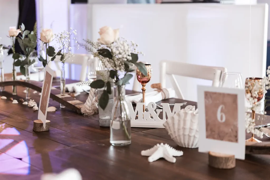 Festlich gedeckter Hochzeitstisch mit Rosen, Muscheln und maritimer Hochzeitsdekoration